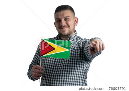 White guy holding a flag of Guyana and points forward in front of him isolated on a white background 76805791