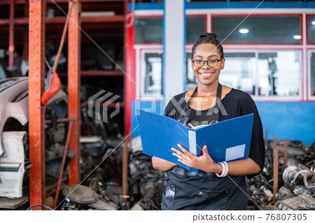 African american worker woman wear spectacles holding clipboard standing in factory auto parts. African american worker woman wear spectacles holding clipboard standing in factory auto parts. 76807305