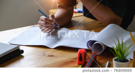 Business engineer hand holding pencil with construction drawing. consulting planning for engineering concept. Business engineer hand holding pencil with construction drawing. consulting planning for engineering concept. 76809000