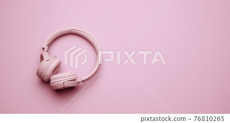 pink wireless headphones on a pink background, banner. Top view on modern gadget 76810265