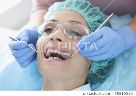 Dentist examining oral cavity of woman patient Dentist examining oral cavity of woman patient 76810550