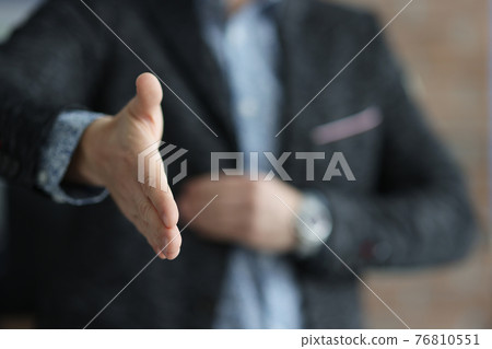 Man in black jacket stretching out his hand for handshake closeup 76810551