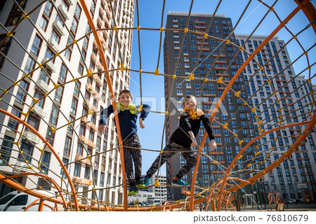 The children are playing on a playground in a school yard. 76810679