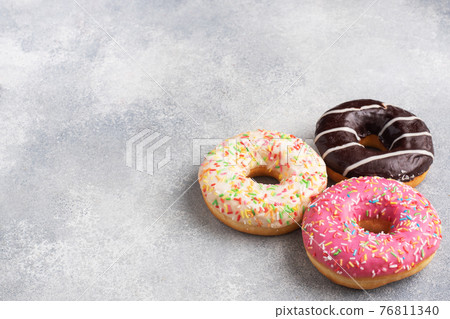 Assortment of donuts in icing on a gray concrete table, copy space. Assortment of donuts in icing on a gray concrete table, copy space. 76811340