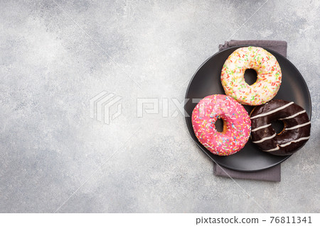 Assortment of donuts in the glaze on a plate, top view copy space. Assortment of donuts in the glaze on a plate, top view copy space. 76811341