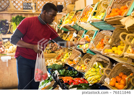 Man looking for vegetables and fruits in greengrocery Man looking for vegetables and fruits in greengrocery 76811846