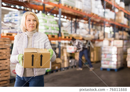 Female warehouse worker carrying cardboard boxes 76811888
