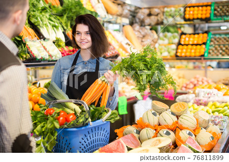 Female shopping assistant helping customer to buy fruit and vegetables in grocery shop Female shopping assistant helping customer to buy fruit and vegetables in grocery shop 76811899