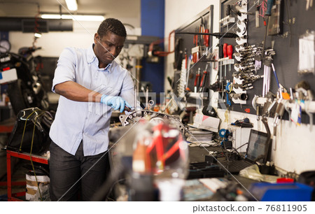 Portrait of man master who is repairing motobike in the workshop Portrait of man master who is repairing motobike in the workshop 76811905