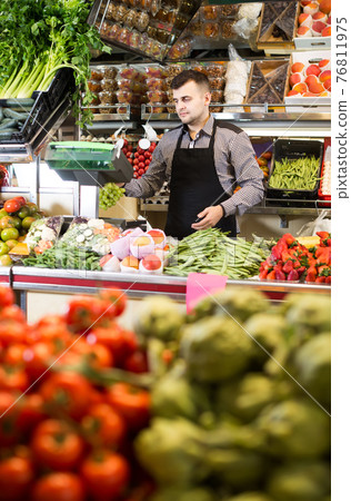 Male shopping assistant weighing grapes in grocery shop 76811975