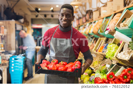 Salesman filling counter with red peppers 76812052