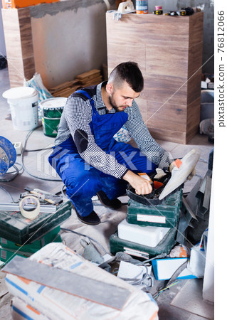 Builder is choosing tools in suitcase for work Builder is choosing tools in suitcase for work 76812066