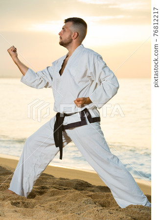 Brunette guy practising karate kata poses 76812217
