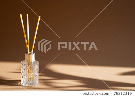 Aromatic reed air freshener on brown background hard shadow. Aromatherapy sticks. Air refresher bottle diffuser. Aesthetic, minimalism. 76812319