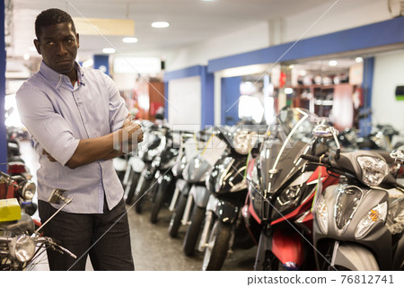 Portrait of adult man buying new motorcycle at modern showroom Portrait of adult man buying new motorcycle at modern showroom 76812741