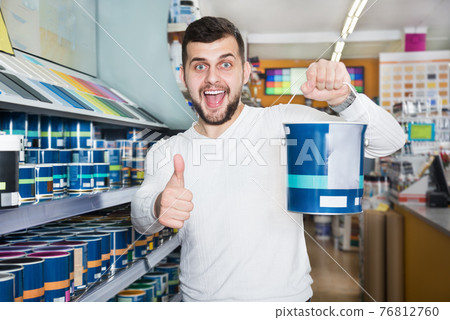Male customer examining various wall paints Male customer examining various wall paints 76812760