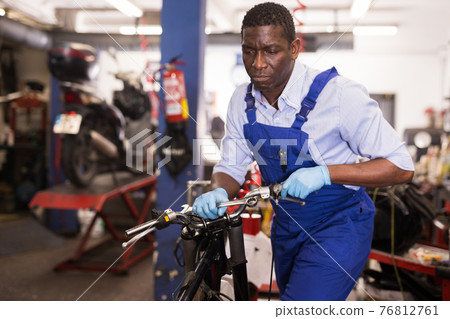 Service engineer repairs a motorcycle steering wheel in a motorcycle service Service engineer repairs a motorcycle steering wheel in a motorcycle service 76812761