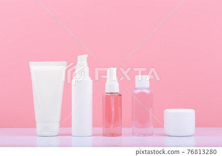 Set of cosmetic products in unbranded white tubes in a row on white table against bright pink background. Set of cosmetic products in unbranded white tubes in a row on white table against bright pink background. 76813280