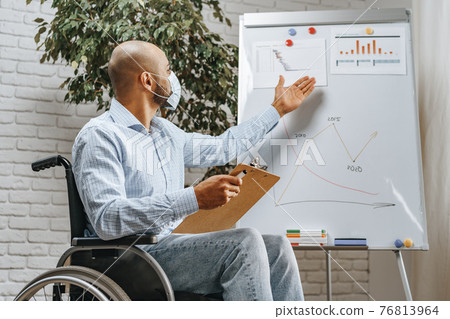Disabled young man making presentation in office wearing medical mask Disabled young man making presentation in office wearing medical mask 76813964