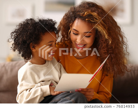 Cute little son giving his mom greeting postcard on Mothers day, celebrating together at home Cute little son giving his mom greeting postcard on Mothers day, celebrating together at home 76814933