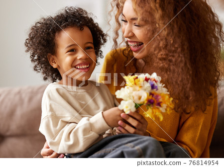 Cute little son giving flower bouquet his mom for Mothers day 76814954