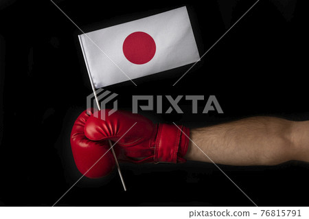 Boxer hand holds flag of Japan. Boxing glove with the Japanese flag. Black background. Boxer hand holds flag of Japan. Boxing glove with the Japanese flag. Black background. 76815791