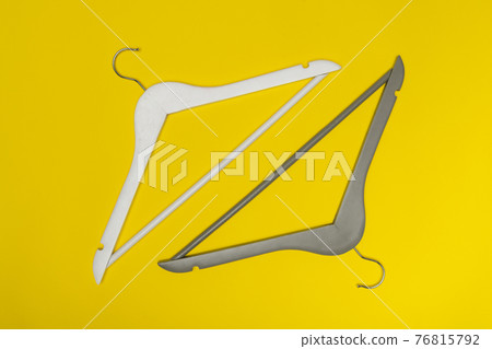 White and gray wooden hangers on yellow top view background. White and gray wooden hangers on yellow top view background. 76815792