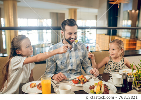 Smiling family sitting at the table and looking happy 76815821