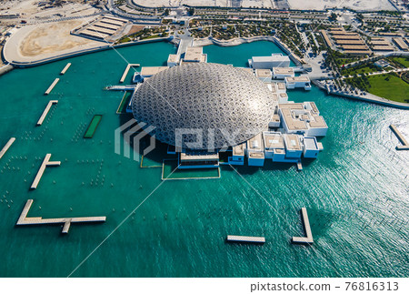 Louvre museum in Abu Dhabi emirate of the United Arab Emirates at sunrise aerial drone view of the building appear to float on the seaside 76816313