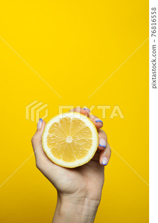 Female hand hold lemon on yellow background Female hand hold lemon on yellow background 76816558