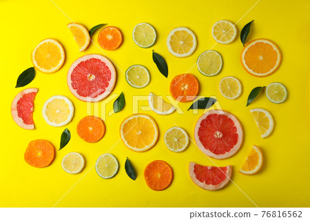 Ripe citrus slices and leaves on yellow background Ripe citrus slices and leaves on yellow background 76816562