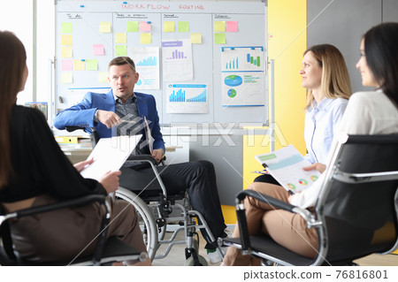 Business coach in wheelchair conducts business meeting of employees Business coach in wheelchair conducts business meeting of employees 76816801
