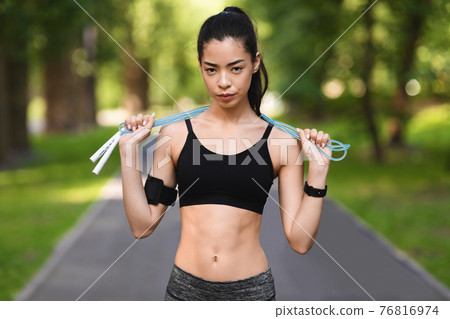 Motivated Fit Asian Woman Posing With Skipping Rope Outdoors, Training In Park Motivated Fit Asian Woman Posing With Skipping Rope Outdoors, Training In Park 76816974