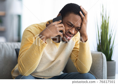 Closeup of sad black guy having conversation on phone 76817501