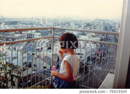 A girl with a bob playing with soap bubbles on the balcony 76819304