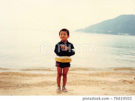 Old film photo: A little boy standing on the beach 76819503