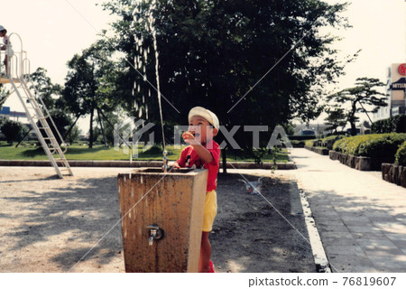 老電影照片：一個男孩在公園的飲水機旁玩耍 76819607