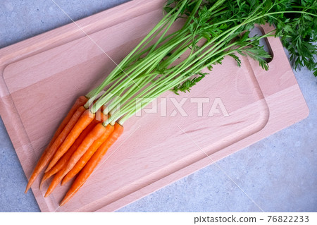 Fresh carrots with leaves on a cutting board Fresh carrots with leaves on a cutting board 76822233