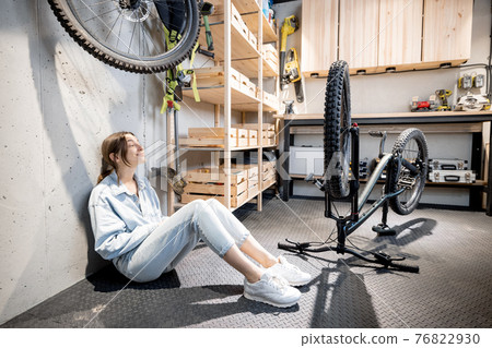 Handywoman with phone and bicycle in the workshop at home 76822930