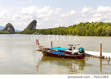 blue motor boat near the pier on the background of green mountains covered with jungle 76822968