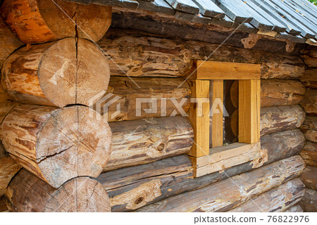 traditional log house side view with a window in a wooden frame 76822976