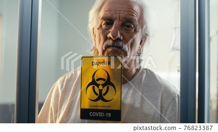 Senior patient behind glass wall in COVID ward 76823387