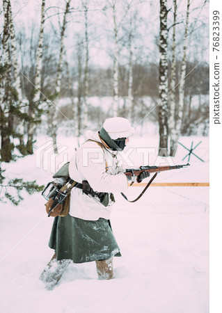 German Wehrmacht Infantry Soldier In World War II Attacking With Rifle In Winter Day. Historical Re-enactment. WWII. German Wehrmacht Infantry Soldier In World War II Attacking With Rifle In Winter Day. Historical Re-enactment. WWII. 76823399