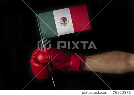 Boxer hand holds flag of Mexico. Boxing glove with the Mexican flag. Black background. Boxer hand holds flag of Mexico. Boxing glove with the Mexican flag. Black background. 76823578