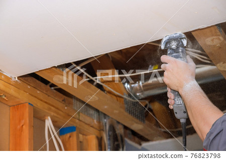 Man cutting gypsum drywall on using angle hand electric power tools 76823798
