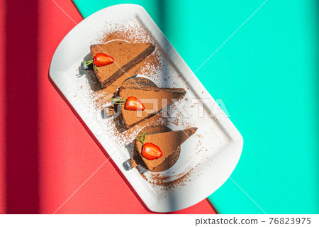 Chocolate truffle cheesecake with strawberries on pink and mint abstract backgrount. 76823975