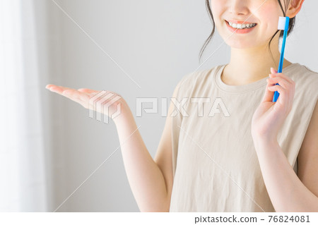 A young woman who recommends while holding a toothbrush A young woman who recommends while holding a toothbrush 76824081