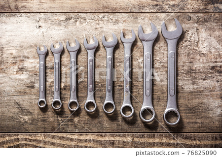 Wrenches of different sizes on wooden background Wrenches of different sizes on wooden background 76825090