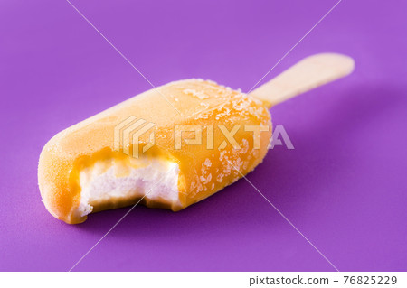 Orange popsicle on violet background 76825229