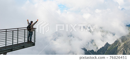 Tourist enjoying of amazing view of mountains and clouds. View from Lomnicky peak in Slovakia. Sport, hiking and active life concept. Tourist enjoying of amazing view of mountains and clouds. View from Lomnicky peak in Slovakia. Sport, hiking and active life concept. 76826451